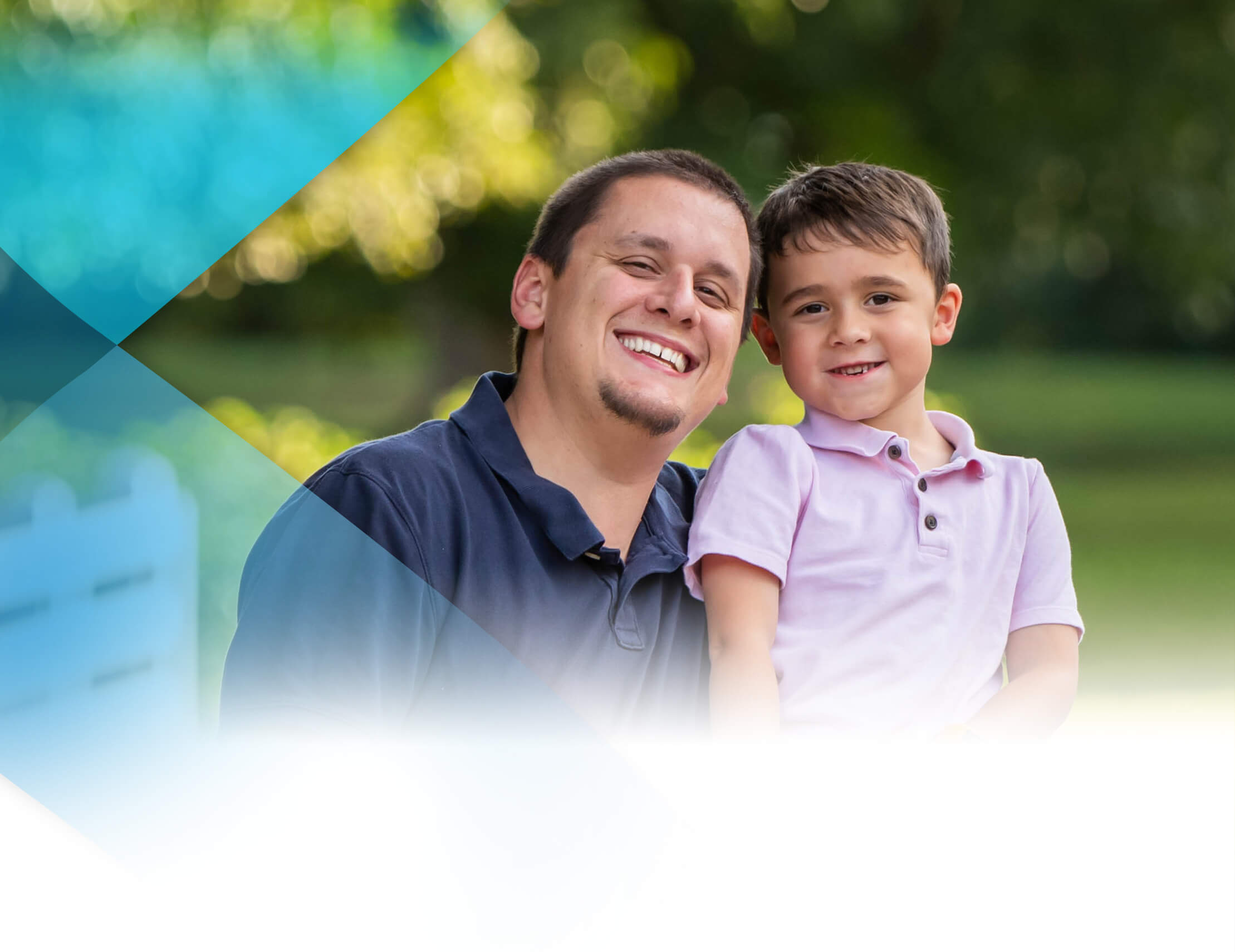 A man smiles at the camera next to a smiling boy.
