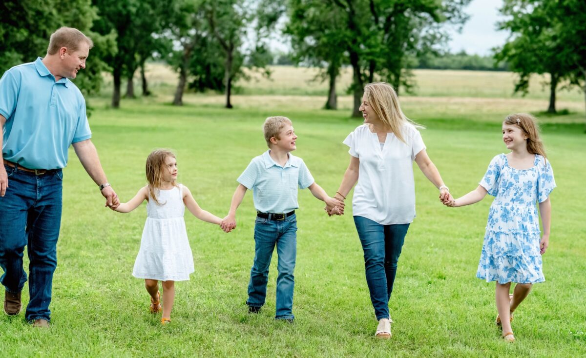 Lee and his family walk through a park holding hands.